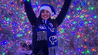 Student in front of Lit Christmas Tree