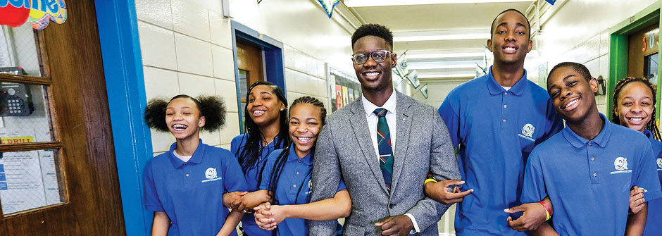 Edmund Adjapong with students walking through a hallway. 