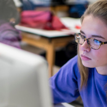 Student sitting in front of a Mac. 