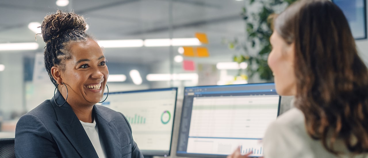 Two colleagues talking and smiling in a work setting.