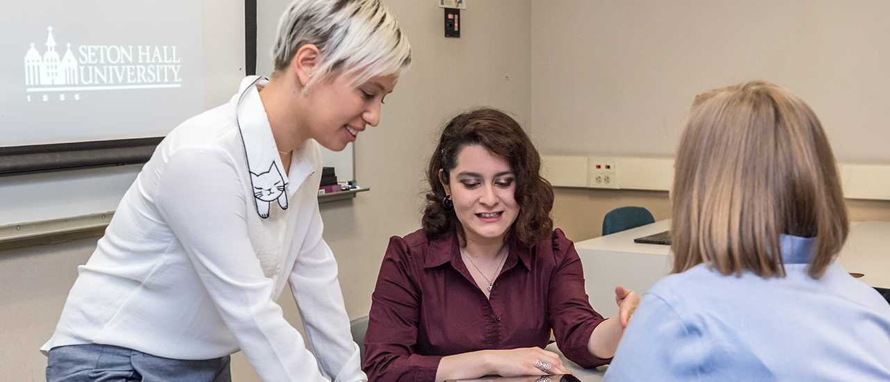 A professor speaking with a group of students in Graduate Studies. 