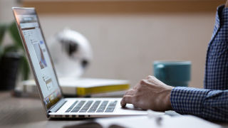 Photo of graduate student Etana Edelmen.An adult typing on a laptop.