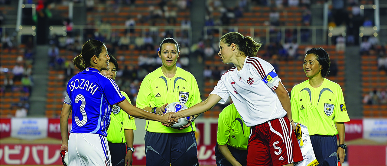 Andrea Neil with her team on the soccer field. Women shaking hands before a soccer match.