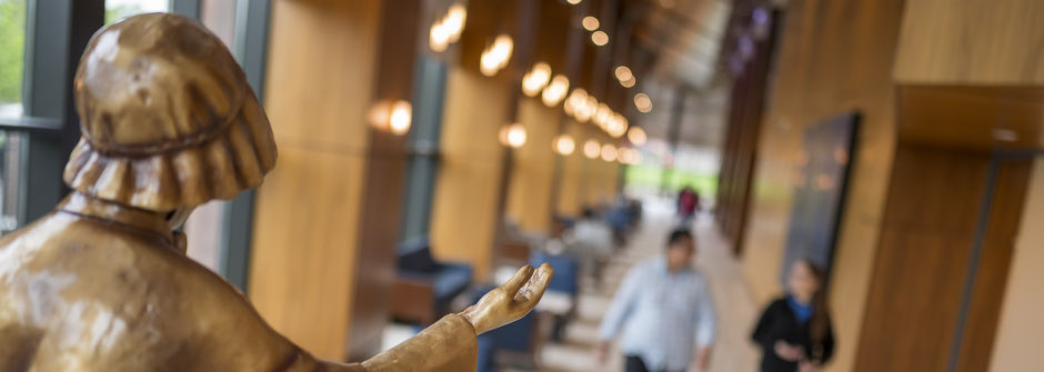 Students walking in Bethany Hall with the statue of St. Elizabeth Ann Seton watching over them.