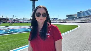 student posing in front of a race track