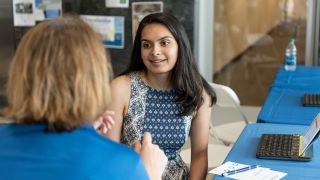 A female faculty member meeting with a female student at a desk with laptops.