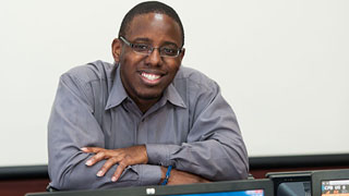 Dwayne Greene standing in front of a book shelf.