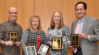 Four winners of the Teacher/Adjunct of the year award with their awards.