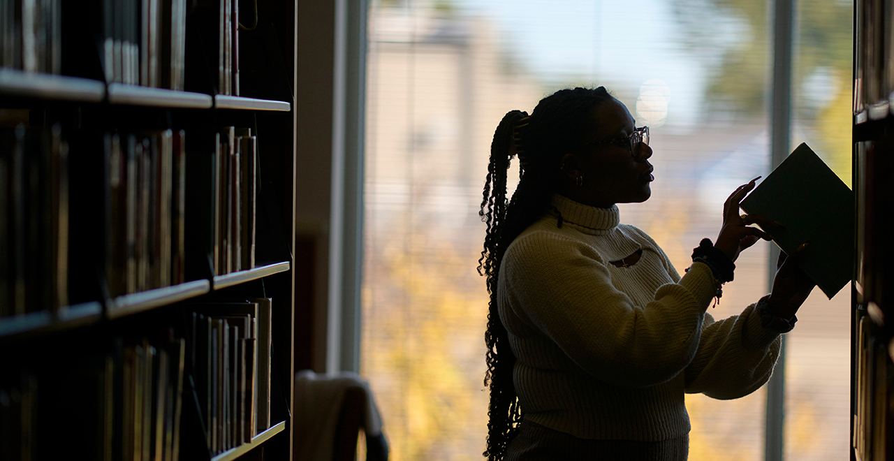 A person taking a book off a shelf in a library.