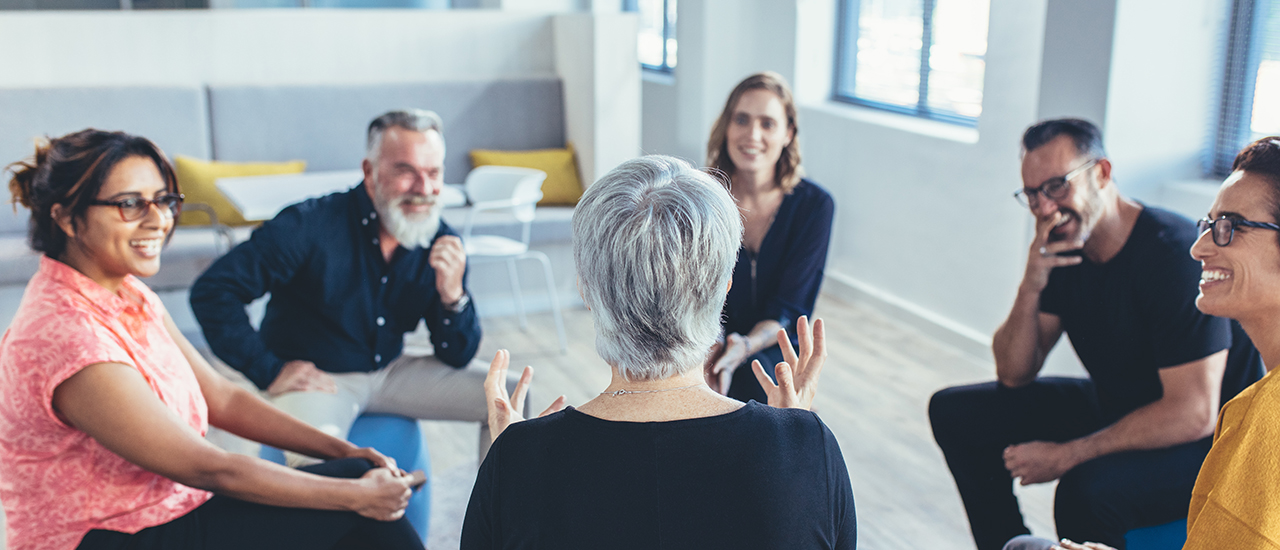 A group of people sitting in a circle have a discussion.