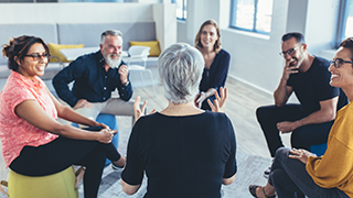 A group of people sitting in a circle have a discussion.