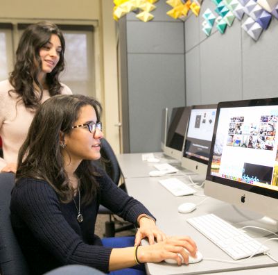 Two SHU MA Comm students working at a computer