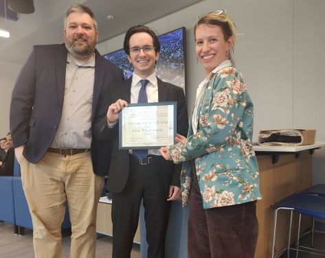 SHU professors pose with a SHU student at a symposium
