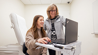 A nursing student with an instructor looking at a monitor. 