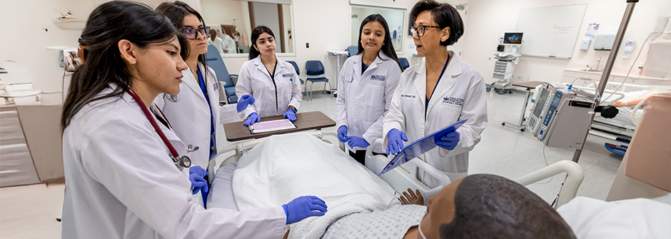 Students and instructor surrounding a mannequin dummy in SHMS during class.