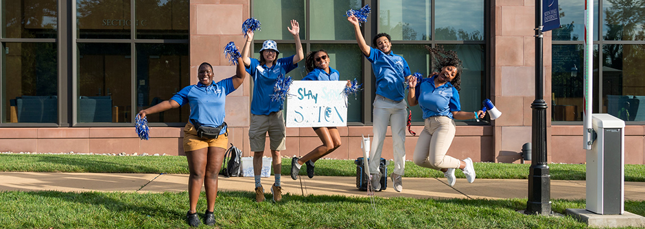 Students cheering on people as they arrive at campus.