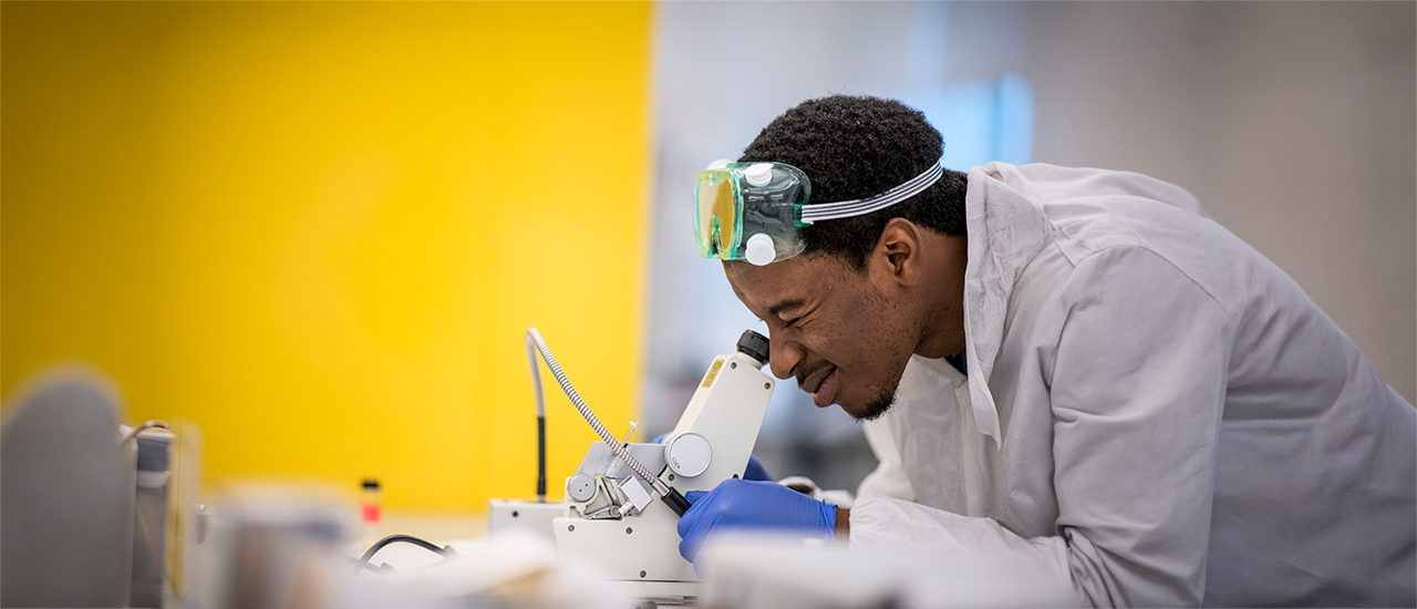 Student leaning over microscope
