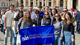 Students in St. Peter's Square holding a SHU flag