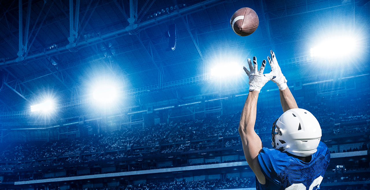 A football player catching a football on a football field.