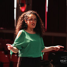 Professor Angela Kariotis Kotsonis speaking on stage to the actors of the performance. 